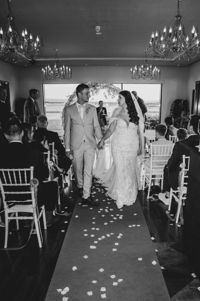 Brautpaar beim Auszug nach der freien Trauung im Sombea Donaueschingen mit Blütenblättern auf dem Mittelgang
